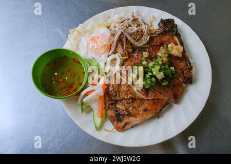 Vietnamesisches Reisgericht (com tam / cơm tấm), serviert mit gegrilltem Schweinefleisch und Fischsauce Stockfoto