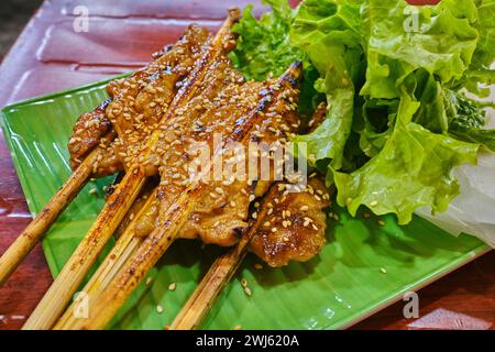 Gegrilltes Schweinefleisch auf Spießen, serviert mit Gemüse und Reispapier Stockfoto