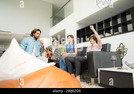 Multiethnische Gruppe von Freunden, die Spaß beim Gitarrenspielen und gemeinsamen Singen zu Hause haben Stockfoto