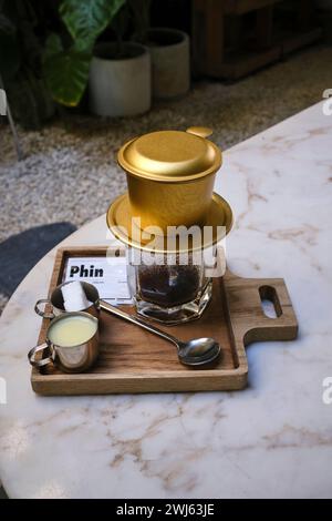 Vietnamesischer Tropffilterkaffee serviert mit Kondensmilch und Zucker auf der Seite Stockfoto