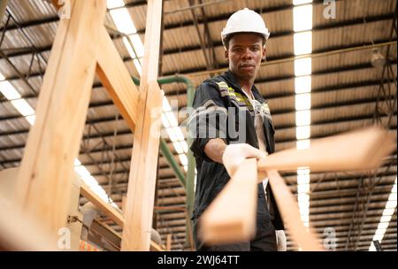 Ein Zimmermann arbeitet in einer Holzfabrik und sammelt Holz, das durch den Holzschneider gelangt ist, in kleine Stücke. Zu senden an BE f Stockfoto