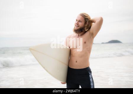 Surfer Mann mit seinem Surfbrett am Strand. Stockfoto