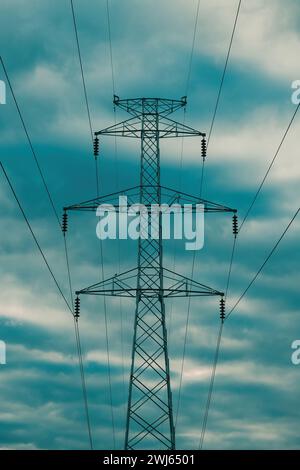 Symmetrische Aufnahme eines Hochspannungsturms aus elektrischem Pylon mit Drähten gegen dramatischen Himmel Stockfoto