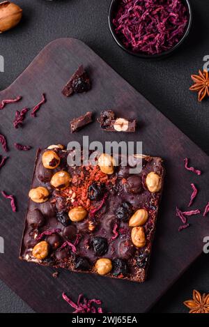 Handgemachte Schokolade mit Beeren, Nüssen und Gewürzen auf dunklem Hintergrund Stockfoto