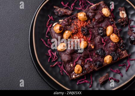 Handgemachte Schokolade mit Beeren, Nüssen und Gewürzen auf dunklem Hintergrund Stockfoto