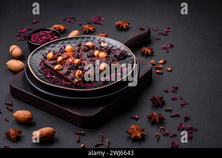 Handgemachte Schokolade mit Beeren, Nüssen und Gewürzen auf dunklem Hintergrund Stockfoto