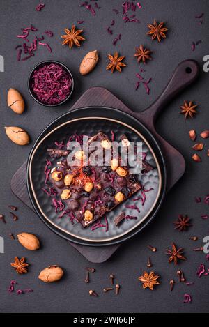 Handgemachte Schokolade mit Beeren, Nüssen und Gewürzen auf dunklem Hintergrund Stockfoto