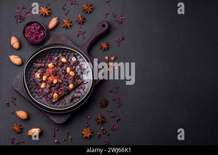 Handgemachte Schokolade mit Beeren, Nüssen und Gewürzen auf dunklem Hintergrund Stockfoto
