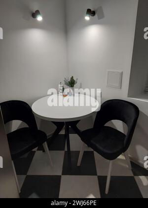 Weißer Holztisch und zwei schwarze Stühle. Dinner Zone. Stockfoto