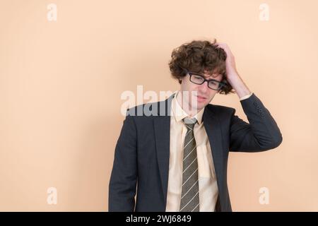 Porträt eines hübschen jungen Mannes mit lockigen Haaren auf beigefarbenem Hintergrund Stockfoto