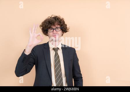 Porträt eines hübschen jungen Mannes mit lockigen Haaren auf beigefarbenem Hintergrund Stockfoto