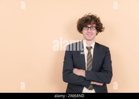 Porträt eines hübschen jungen Mannes mit lockigen Haaren auf beigefarbenem Hintergrund Stockfoto
