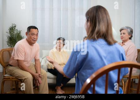 Gruppe von älteren und asiatischen Senioren, die sich mit der Krankenschwester im Altersheim unterhalten Stockfoto