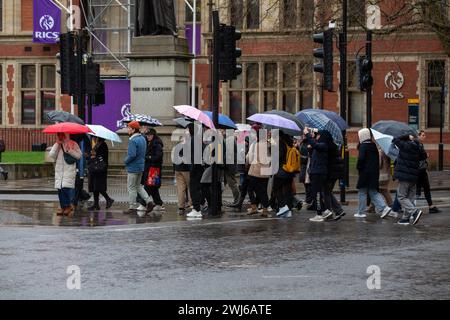 London, UK, 13. Februar 2024 Touristenwarteschlange im Regen mit Regenschirmen, um Fotos von der ikonischen Red Phone Box in London zu machen und die Sehenswürdigkeiten in London trotz Regen zu genießen Credit: Richard Lincoln/Alamy Live News Stockfoto