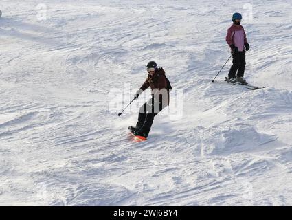 West Dover, Vermont, USA - 31. Dezember 2023: Ein Skifahrer und ein Snowboarder gleiten am Silvestertag 2023 eine Skipiste hinunter. Stockfoto