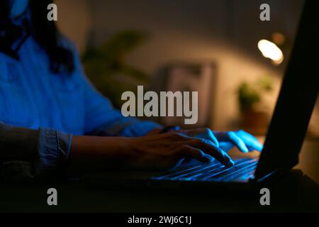 Nahaufnahme Einer Frau, Die Nachts Zu Hause Ein Notebook Benutzt, Mit Fingern, Die Auf Der Tastatur Tippen Stockfoto