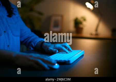 Nahaufnahme Einer Frau, Die Nachts Zu Hause Den Computer Benutzt, Mit Fingern, Die Auf Der Tastatur Tippen Stockfoto