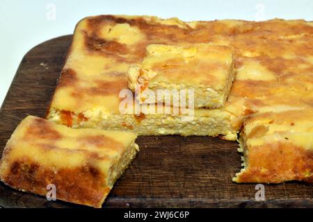 Ein Kuchen, gebacken aus Hüttenkäse und Kürbis und Stücke daraus liegen auf einem Schneidebrett. Stockfoto