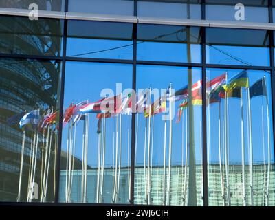 Straßburg, Frankreich - 4. März 2022: Reflexion im Fenster des Winkels der ukrainischen Flagge neben allen eu-Mitgliedsflaggen vor dem Europäischen Parlament - klarer blauer, friedlicher Himmel Stockfoto