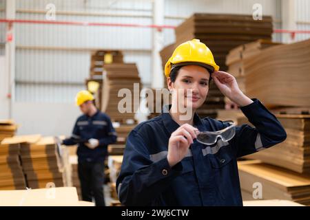 Porträt einer Lagerarbeiterin, die eine Brille im Lager hält. Dies ist ein großes Lagergut für Papierverpackungen und -Distribution Stockfoto