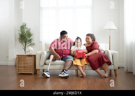 Eine große Familie mit einem Vater, der eine Beinprothese trägt, schenkt einer Tochter, die in der Schule gut geht und Anerkennung erhält Stockfoto