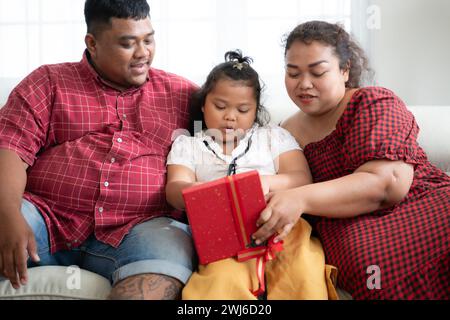 Eine große Familie mit einem Vater, der eine Beinprothese trägt, schenkt einer Tochter, die in der Schule gut geht und Anerkennung erhält Stockfoto