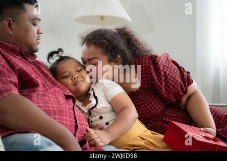 Eine große Familie mit einem Vater, der eine Beinprothese trägt, schenkt einer Tochter, die in der Schule gut geht und Anerkennung erhält Stockfoto