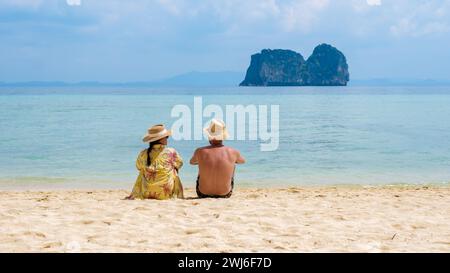 Ein paar Männer und Frauen sitzen am tropischen Strand auf der Insel Koh Ngai Stockfoto