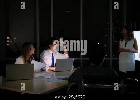 Gruppe von Brokern, internationalen Aktienhändlern, die nachts aktiv im Büro arbeiten, alle streben nach dem Erfolg des Teams. Stockfoto