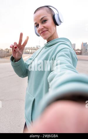 Vertikale Portrait lächelnde Sportlerin, die draußen ein Selfie mit ihrem Smartphone macht. Stockfoto