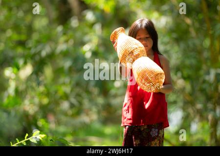 Kleines asiatisches Mädchen in rotem Kleid, das Angelausrüstung im Wald hält, Lural Thailand Living Life Konzept Stockfoto