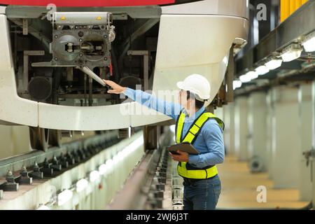 Nachdem der Elektrozug in der Werkstatt des Elektrozugs geparkt ist, inspiziert der Elektrozugnachingenieur den Elektrozug Stockfoto