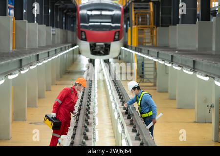 Nachdem der Elektrozug in der Reparaturwerkstatt für Elektrozüge geparkt wurde, prüfen Ingenieur und Techniker des Elektrozugs mit Werkzeugen Stockfoto