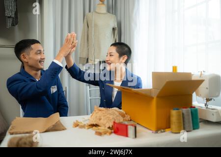 Beide asiatischen Modedesigner arbeiten mit Nähmaschinen im Hochzeitskleiderladen Stockfoto