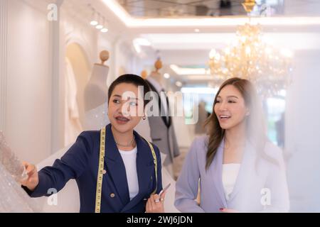 Beide asiatischen Modedesigner arbeiten im Hochzeitskleiderladen mit Hochzeitskleidern Stockfoto