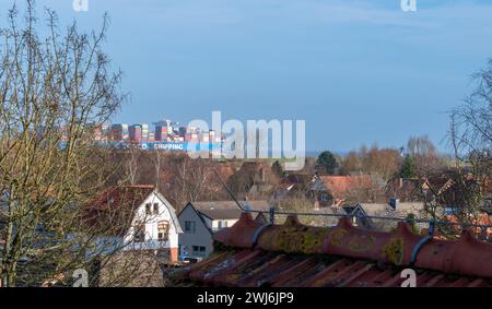 Ein riesiges Containerschiff auf der Elbe, das am 25. Dezember 2023 den Ort Altenbruch bei Cuxhaven überquert. Stockfoto