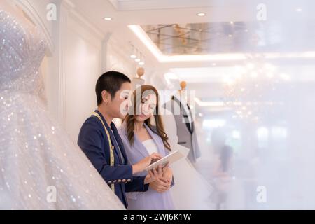 Beide asiatischen Modedesigner arbeiten im Hochzeitskleiderladen mit Hochzeitskleidern Stockfoto