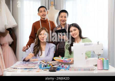 Gruppe asiatischer Modedesigner, die mit Nähmaschinen im Hochzeitskleiderladen arbeiten Stockfoto