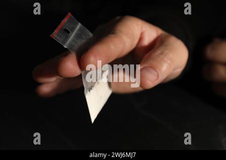 Drogensucht. Mann mit Plastiktüte Kokain auf dunklem Hintergrund, Nahaufnahme Stockfoto