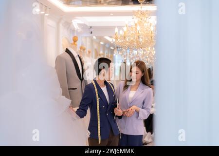 Beide asiatischen Modedesigner arbeiten im Hochzeitskleiderladen mit Hochzeitskleidern Stockfoto