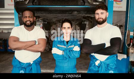 Porträt lächelnder Mechaniker, die in der Autowerkstatt stehen und Daumen nach oben zeigen Stockfoto