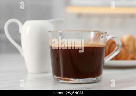 Aromatischer Kaffee in Glasbecher auf weißem Marmortisch Stockfoto