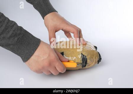 Schmuggel und Drogenhandel. Mann, der ein Paket mit Betäubungsmitteln mit einem Koffer auf weißem Hintergrund öffnet, Großaufnahme Stockfoto