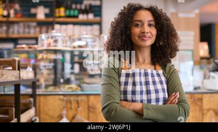 Porträt Einer Selbstbewussten Jungen Frau Mit Schürze, Die Im Lebensmittelgeschäft Arbeitet Stockfoto