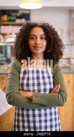 Porträt Einer Selbstbewussten Jungen Frau Mit Schürze, Die Im Lebensmittelgeschäft Arbeitet Stockfoto