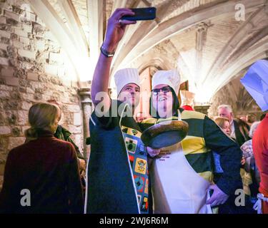 London, UK, 13. Februar 2024. Die Teilnehmer fliehen dem Regen in die Gildenhalle, um Essen zu essen und den Kostümwettbewerb zu beurteilen, der sich in den Innenräumen bewegte. Beim jährlichen Inter Livery Pancake Race treten normalerweise Teams von Livery-Mitgliedern der Worshipful-Unternehmen der City of London an den Fun Pancake-Rennen am Faschingsdienstag im Guildhall Yard an, entweder in schickem Kleid oder voller Insignien. Wegen anhaltendem Regen mussten die eigentlichen Rennen kurzfristig abgesagt werden, aber Teilnehmer und Richter genießen einen Fotoruf, bevor sie in die Gildenhalle gehen, um Essen und Kostüme zu beurteilen. Stockfoto