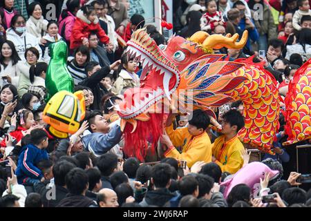 Peking, Chinas Provinz Jiangxi. Februar 2024. Die Menschen interagieren mit Schauspielern des Drachentanzes aus Holzbänken in Nanchang, ostchinesischer Provinz Jiangxi, 12. Februar 2024. Menschen in ganz China genießen Tempelmessen, Laternen-Shows und andere Veranstaltungen, um das chinesische Neujahrsfest zu feiern und die festliche Atmosphäre zu genießen. Quelle: Bao Gansheng/Xinhua/Alamy Live News Stockfoto