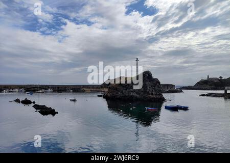 Ruhiger Hafen mit Booten, umgeben von Felsformationen unter einem bewölkten Himmel, verströmt eine ruhige und friedliche Atmosphäre Stockfoto