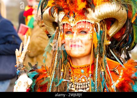 Maastricht, Niederlande. Februar 2024. Eine Frau mit farbenfroher Gesichtsfarbe und auffälligem Kostüm nimmt am Karnevalssonntag in Maastricht Teil. Anna Carpendale/Alamy Live News Stockfoto