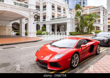 Raffles Hotel in Singapur mit rotem Lamborghini Supercar, der draußen geparkt ist. Stockfoto